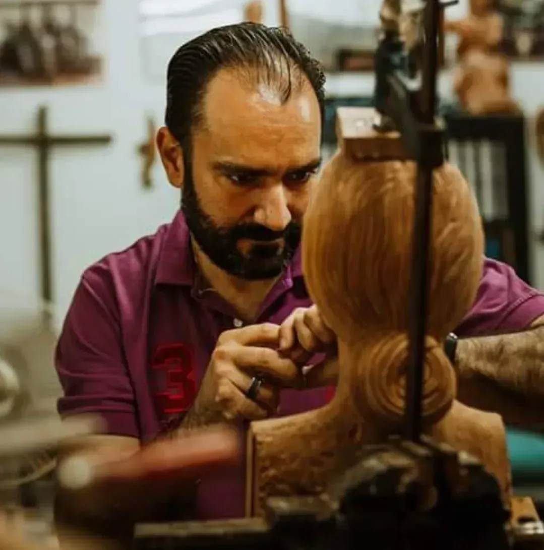 Un peluquero recorta el cabello de un cliente, concentrado en un corte de pelo minucioso en un salón de belleza.