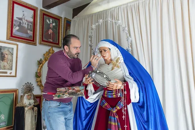 Dos personas vestidas con coloridos trajes tradicionales están de pie en el interior de un edificio