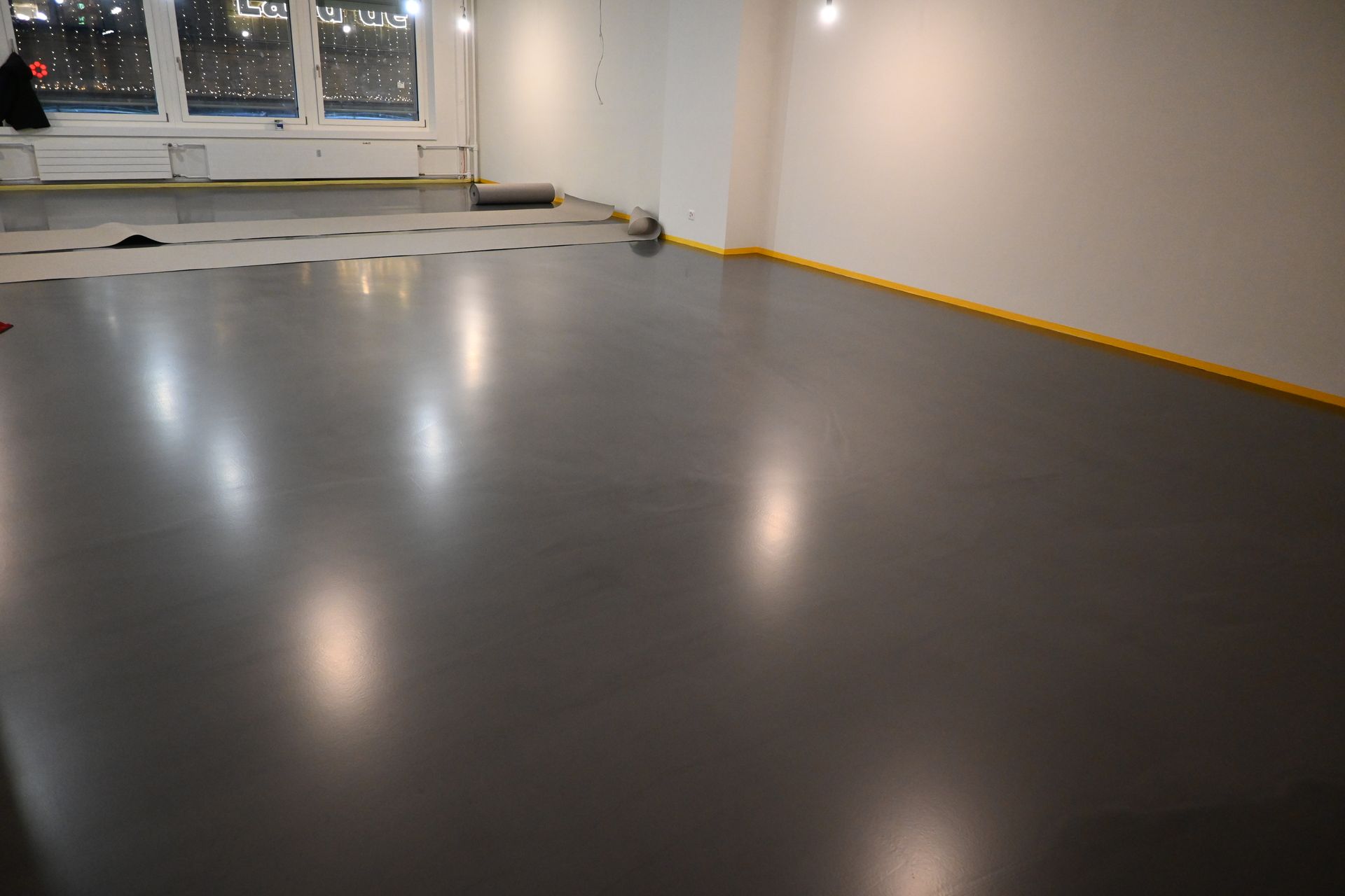 Ein großer, leerer Raum mit grauem Boden und weißen Wänden.