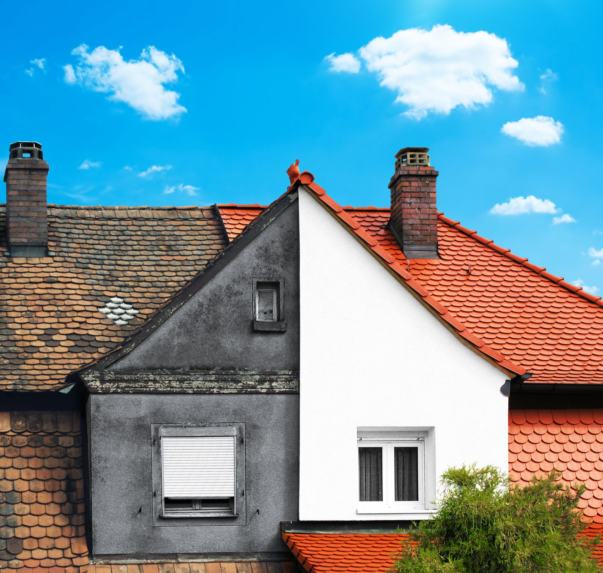 Deux façades de maisons mitoyennes aux murs gris et blancs contrastés, sous des toits de tuiles rouges, se détachant sur un ciel bleu.