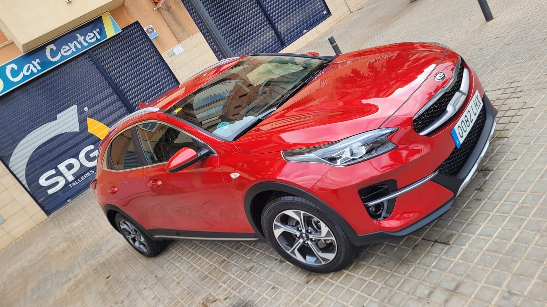 Un coche rojo está aparcado delante de un centro de coches.