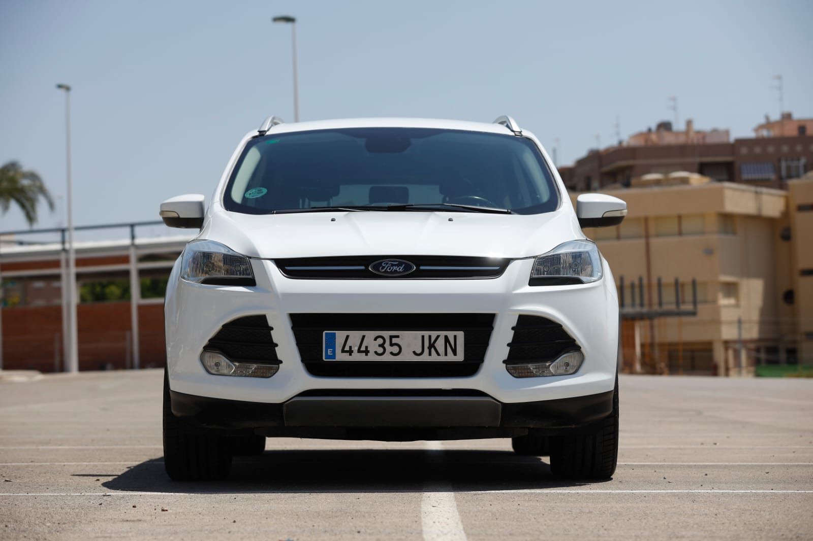 Un coche Ford blanco está estacionado en un estacionamiento.