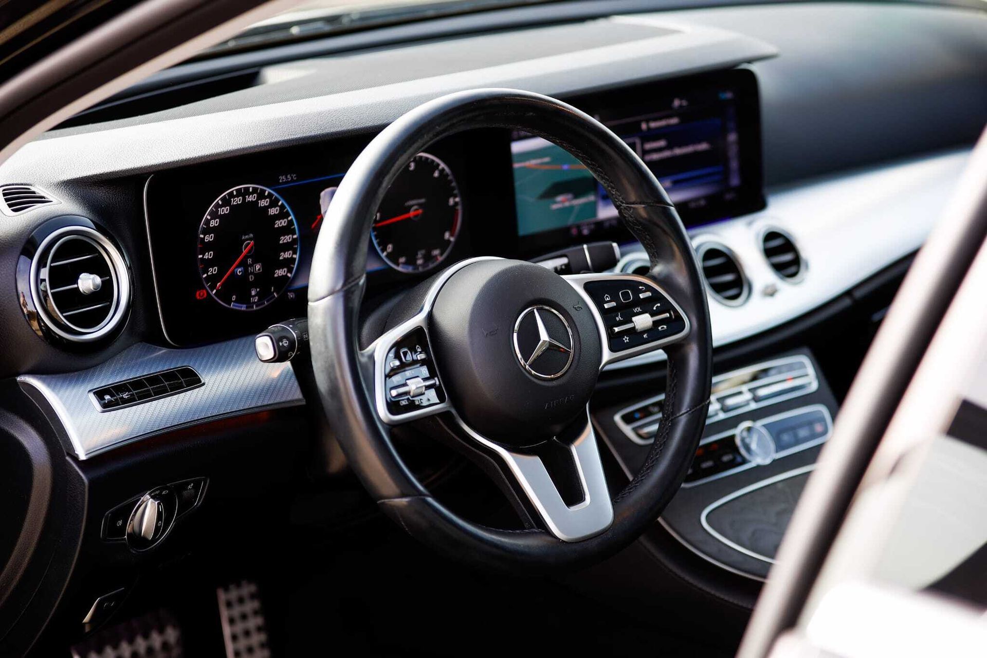 El interior de un automóvil Mercedes Benz con volante y tablero de instrumentos.