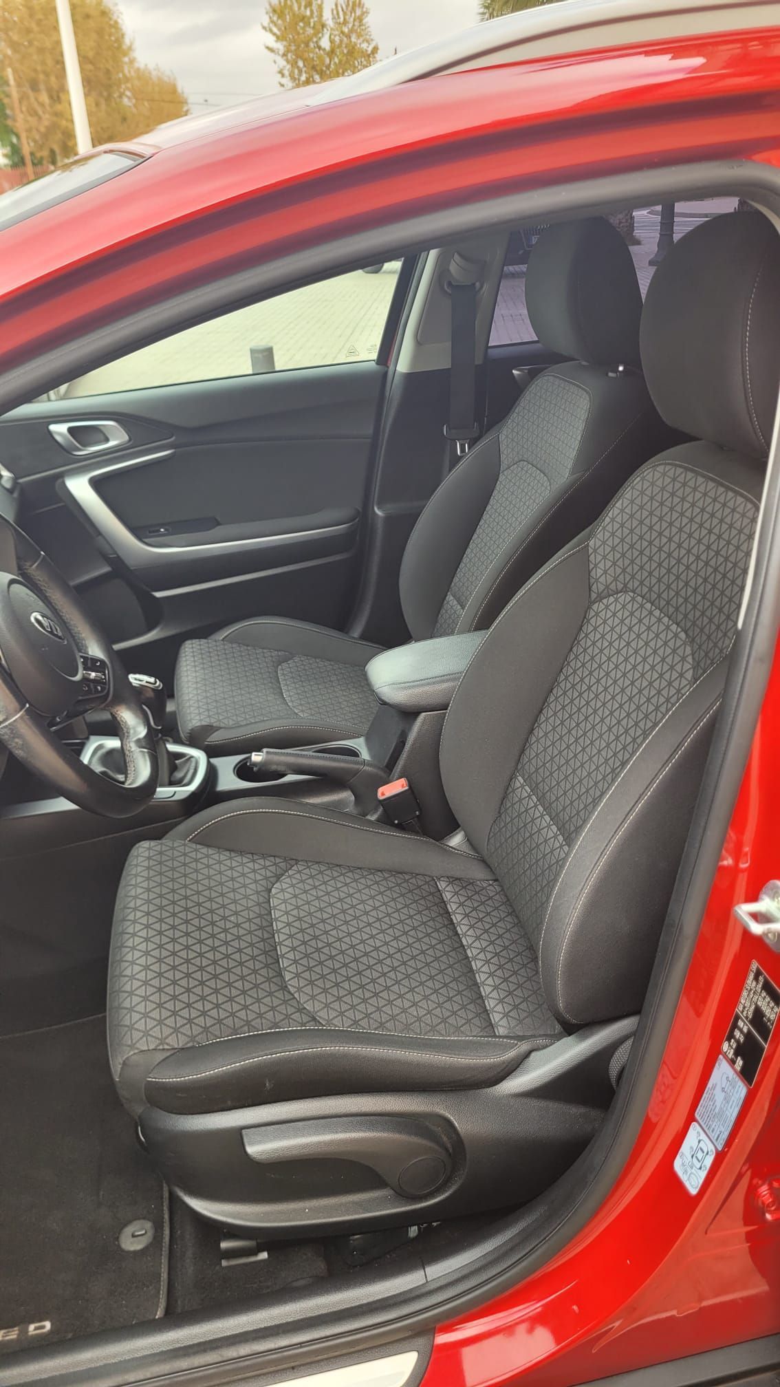 El interior de un coche rojo con asientos negros y un volante.