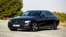 Un Mercedes Benz negro está estacionado al costado de una carretera.