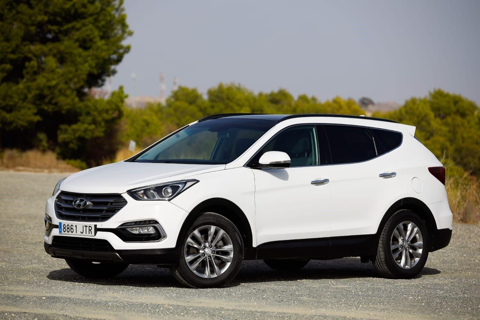 Un Hyundai Santa Fe blanco está estacionado en un camino de grava.