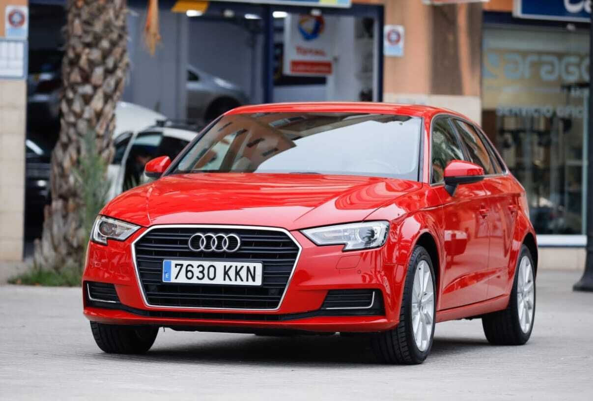 Un Audi A3 rojo está estacionado frente a un edificio.