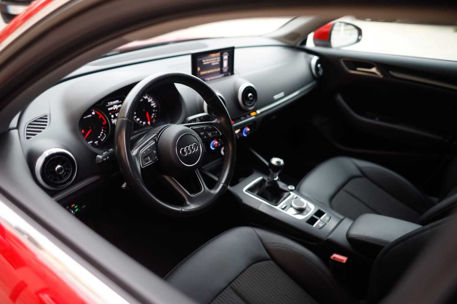 El interior de un coche rojo con asientos negros y un volante.