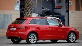 Un coche rojo está aparcado delante de un garaje.