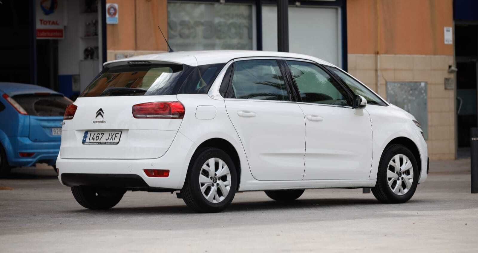 Un coche blanco está estacionado en un estacionamiento frente a un edificio.