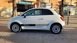 Un coche blanco está estacionado en una acera frente a un edificio.