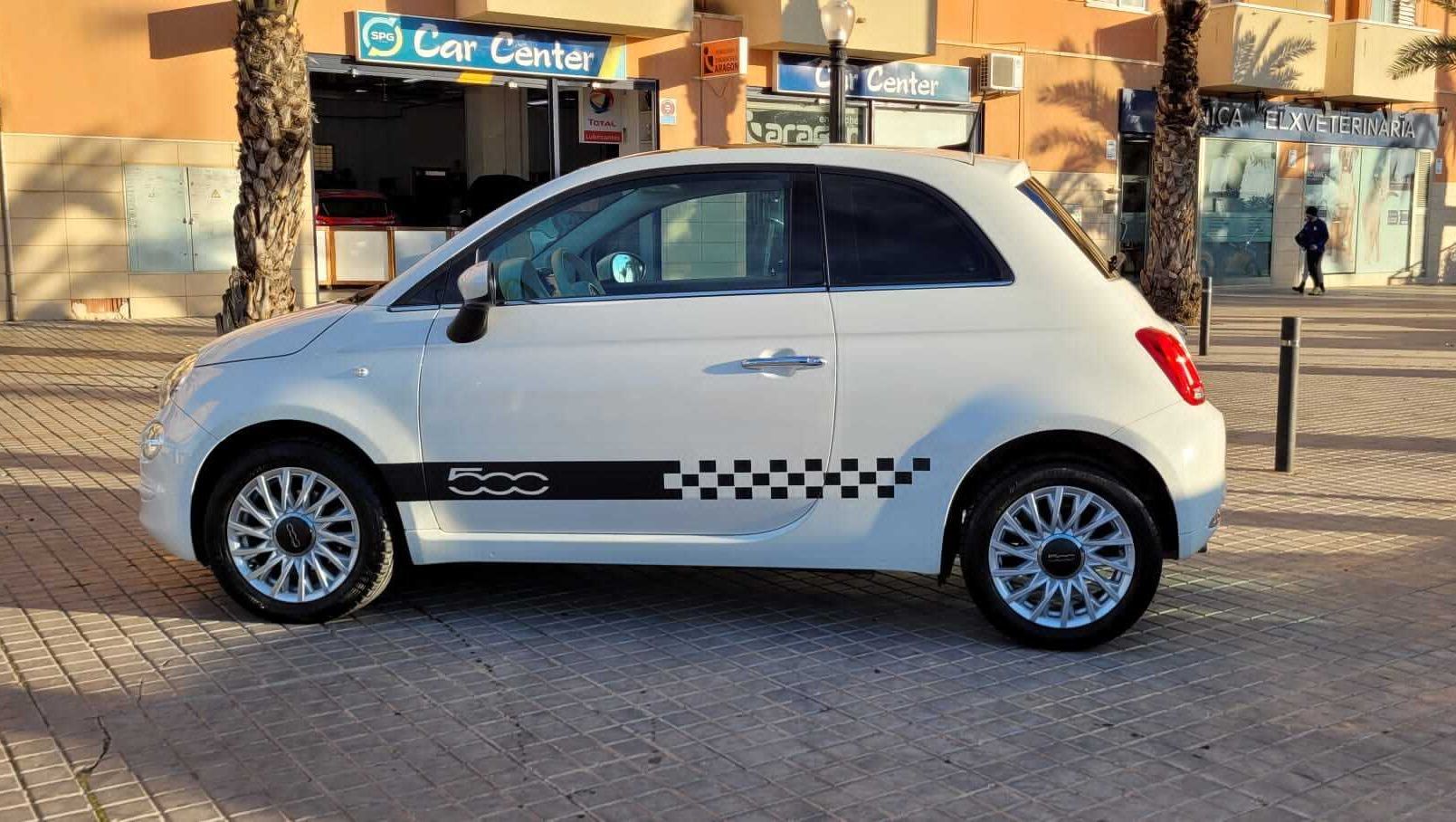 Un coche blanco está aparcado delante de una tienda llamada centro de coches.