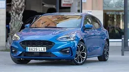 Un Ford Focus hatchback azul está estacionado frente a un edificio.
