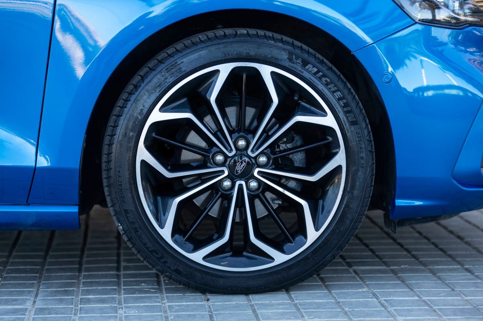 Un primer plano de una rueda de automóvil azul con un neumático sobre ella.