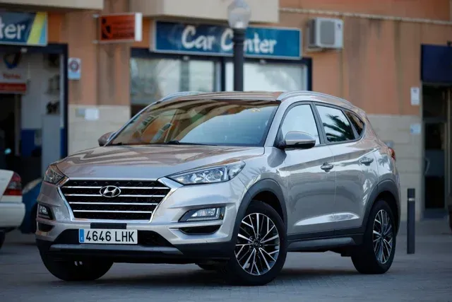 Un Hyundai Tucson plateado está estacionado frente a un centro de automóviles.