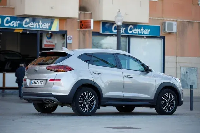 Un coche plateado está aparcado delante de un centro de coches.