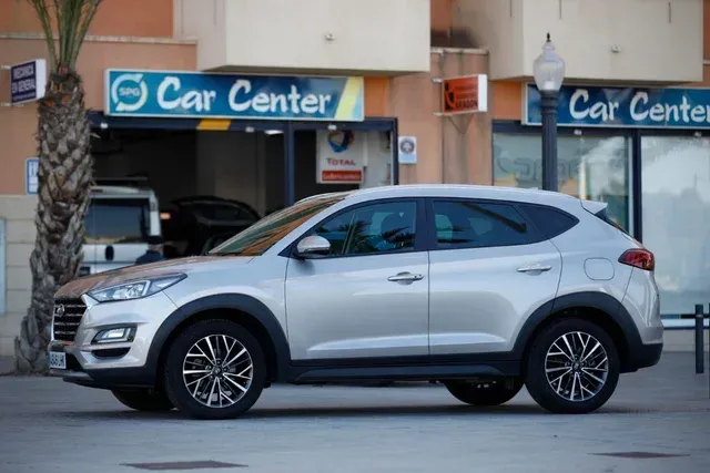 Un coche plateado está aparcado delante de un centro de coches.