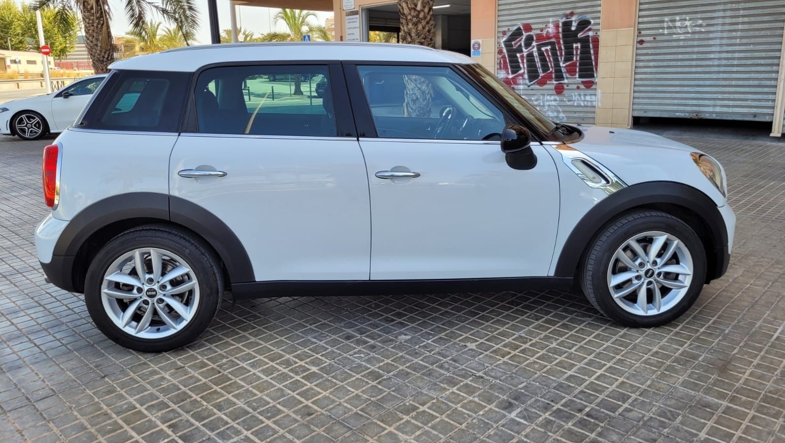 Un Mini Cooper Countryman blanco está estacionado en un estacionamiento.