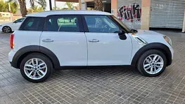 Un Mini Cooper Countryman blanco está estacionado en un estacionamiento.
