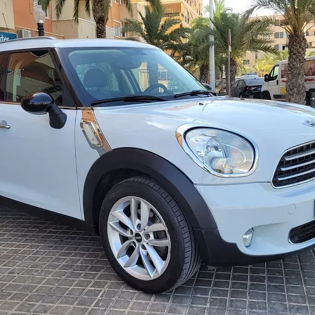 Un mini cooper blanco está estacionado en una acera de ladrillos