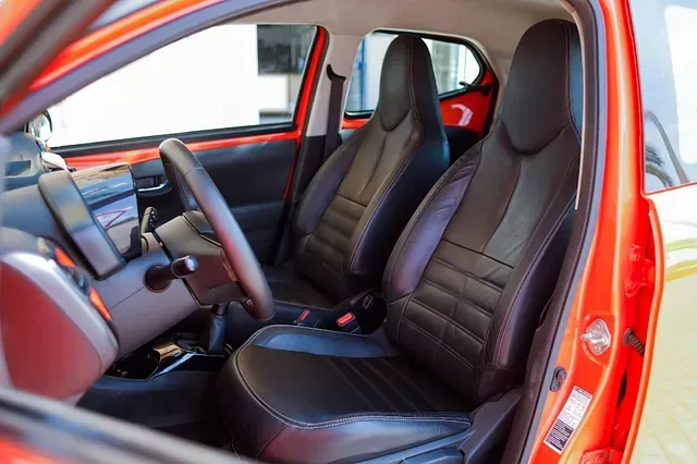 El interior de un coche rojo con asientos negros y un volante.