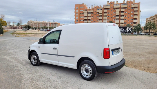 Una camioneta blanca está estacionada en un estacionamiento frente a un edificio.