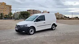 Una camioneta blanca está estacionada en un estacionamiento frente a un edificio.