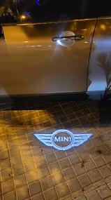 Un Mini Cooper está estacionado en una acera de ladrillos por la noche.