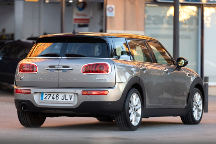 Un Mini Cooper Clubman gris está estacionado frente a un edificio.