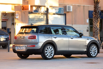 Un Mini Cooper Clubman plateado está estacionado frente a un edificio.