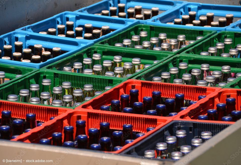 Kisten mit Glasflaschen in verschiedenen Farben: blau, grün und rot. Die Flaschen haben silberne oder blaue Verschlüsse.