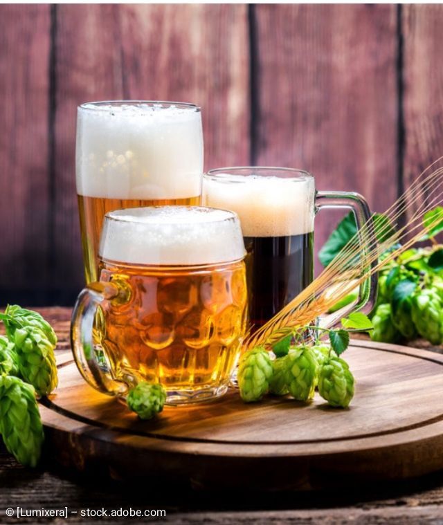 Cocktail auf einer Bar zusammen mit zwei anderen Getränken, garniert mit einer Orangenscheibe, einer Kirsche und einem schwarzen Strohhalm.