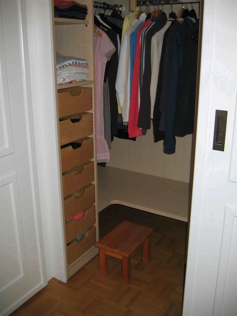 Ein Schrank voller Kleidung und ein kleiner Holzhocker