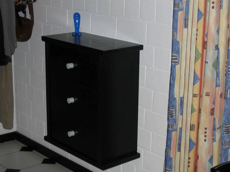 Eine schwarze Kommode hängt an einer weißen Ziegelwand