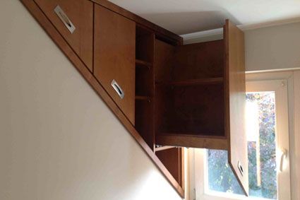 In die Ecke einer Treppe ist ein Holzschrank eingebaut.