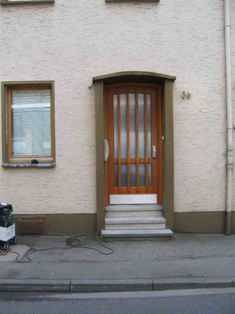 Ein weißes Backsteingebäude mit einer Holztür und Treppe