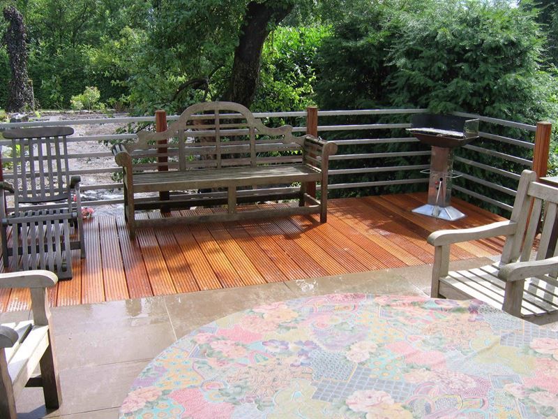 Eine Holzterrasse mit einer Bank und Stühlen darauf