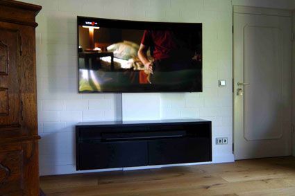 Ein Flachbildfernseher ist an der Wand über einem schwarzen Entertainment-Center montiert.