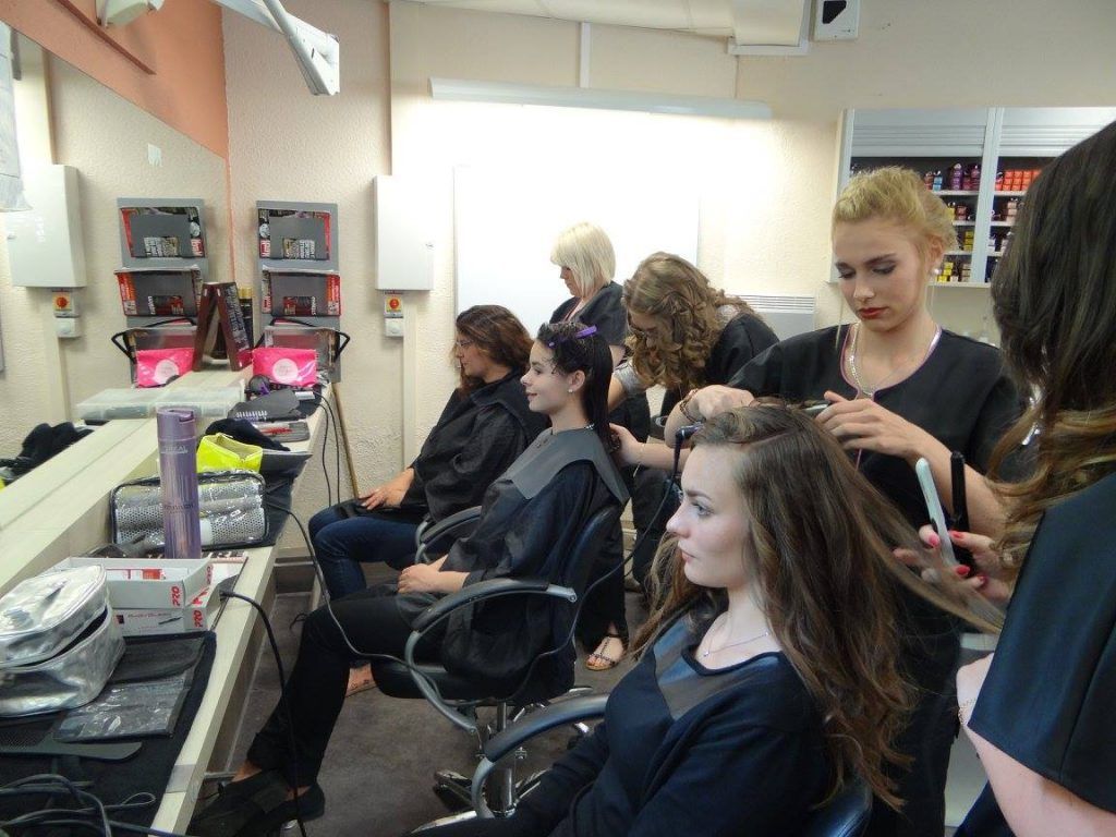 Les élèves coiffeurs s'exercent sur des mannequins et des clients dans une salle de classe.