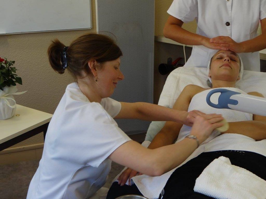 Une femme reçoit un soin en spa, prodigué par deux esthéticiennes.