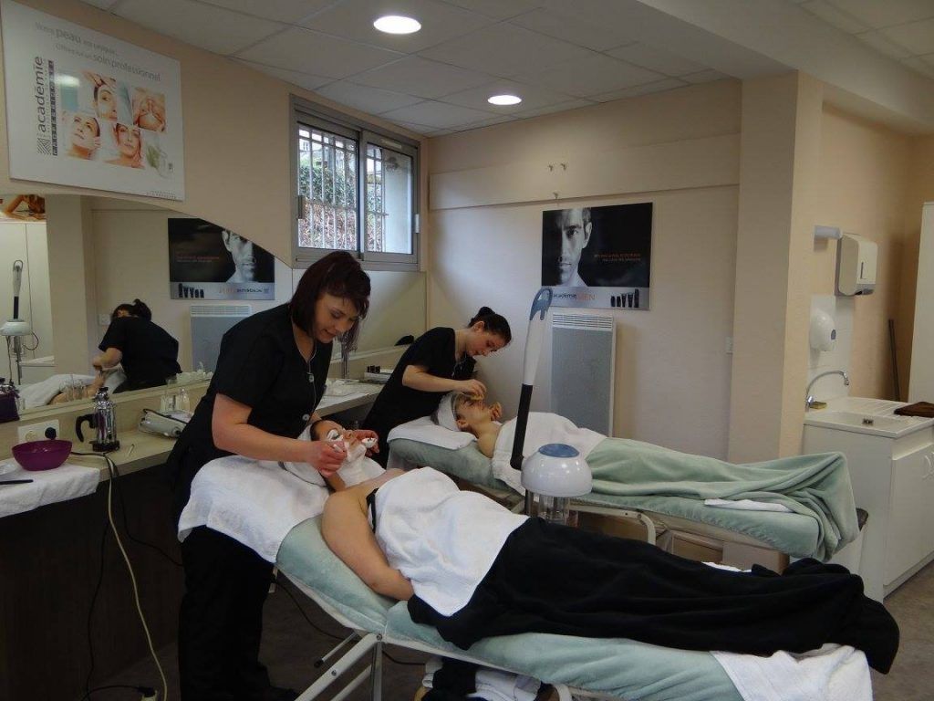 Deux femmes reçoivent des soins du visage dans un salon. Des esthéticiennes s'occupent de leur visage près de fenêtres lumineuses.