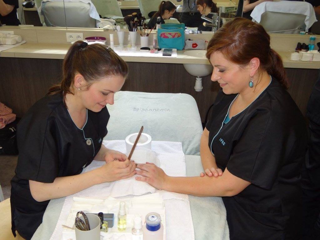 Une femme se fait faire une manucure par une professionnelle dans un salon de beauté.