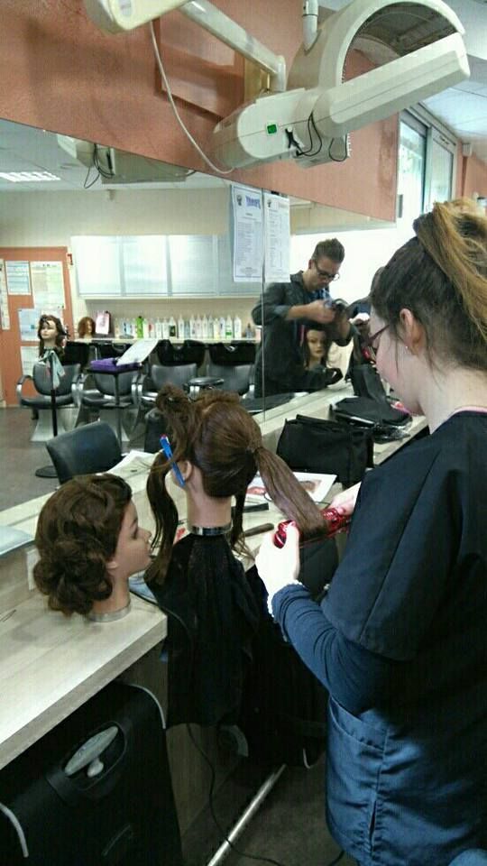 Les élèves coiffeurs s'entraînent sur des mannequins dans un décor ressemblant à un salon de coiffure.