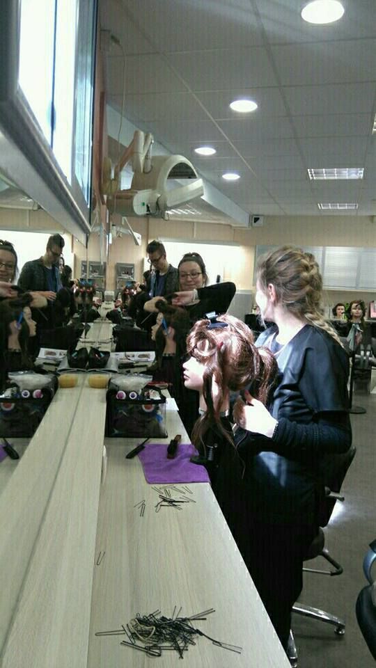 Des élèves en coiffure travaillent sur des têtes de mannequin dans un salon de coiffure.