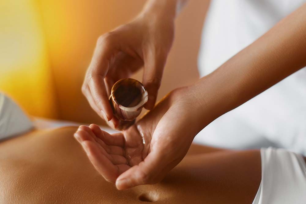 Des mains versant de l'huile sur le ventre d'une autre personne lors d'un massage.