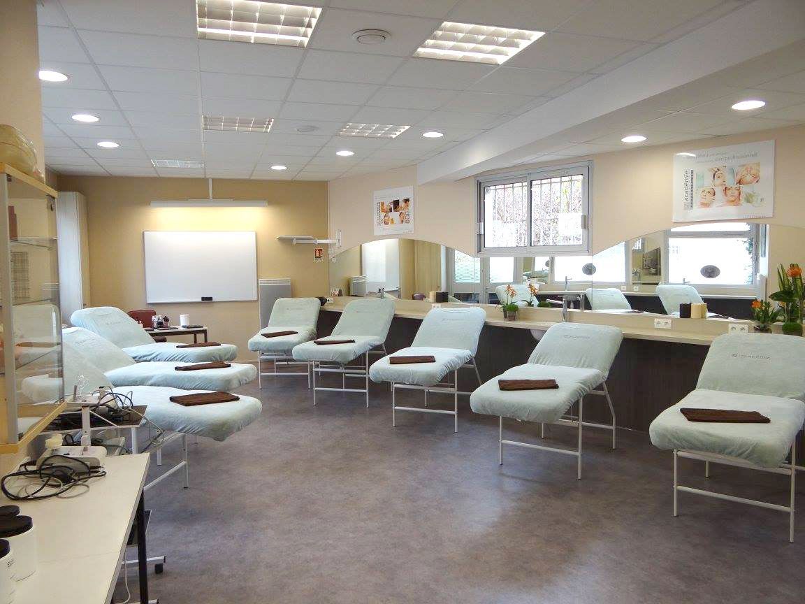 Salle de spa ou de soins avec plusieurs tables de massage, des miroirs et un tableau blanc.