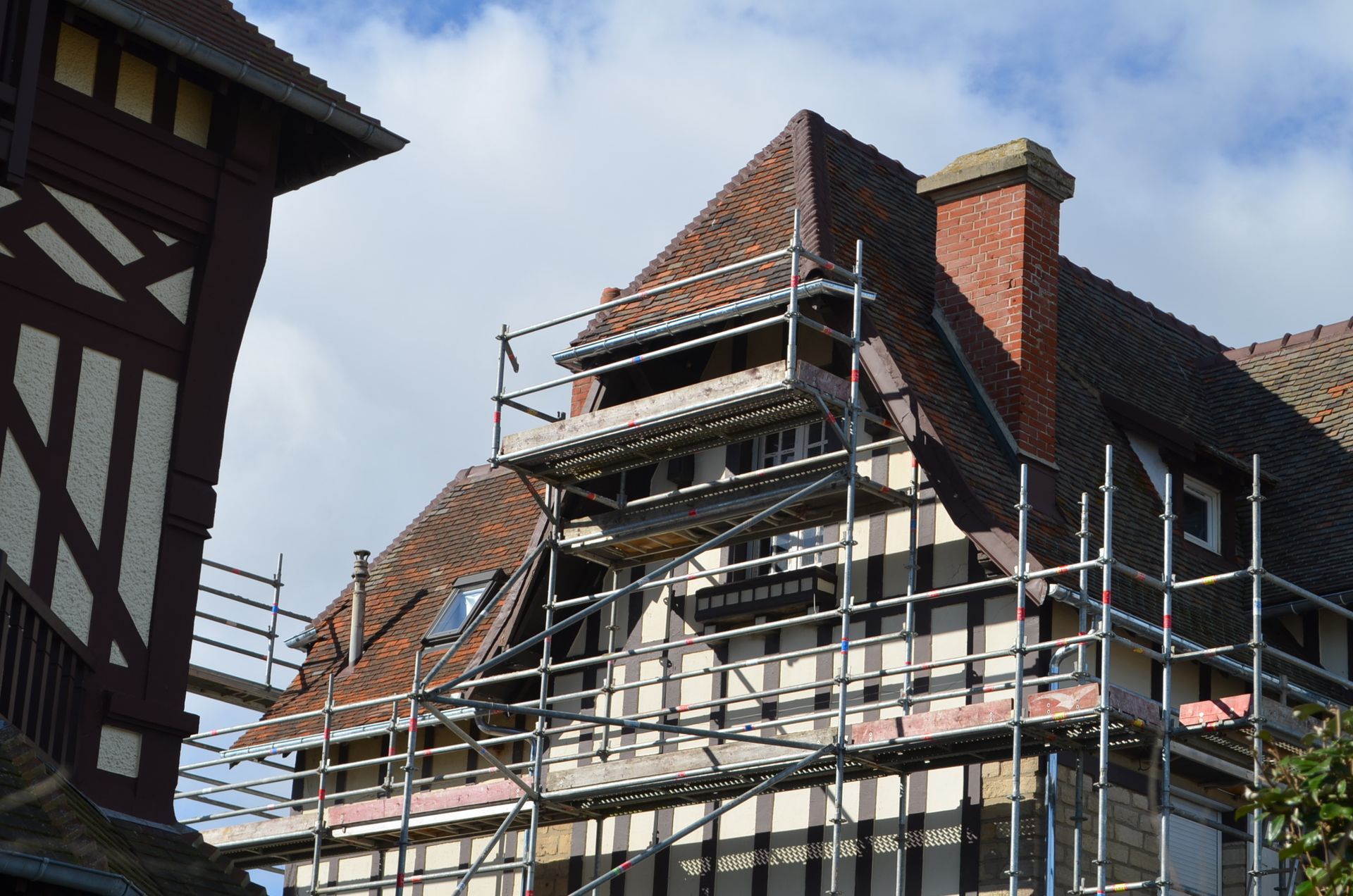 Bâtiment en briques sur échafaudage, en rénovation, à côté d’une structure à ossature en bois