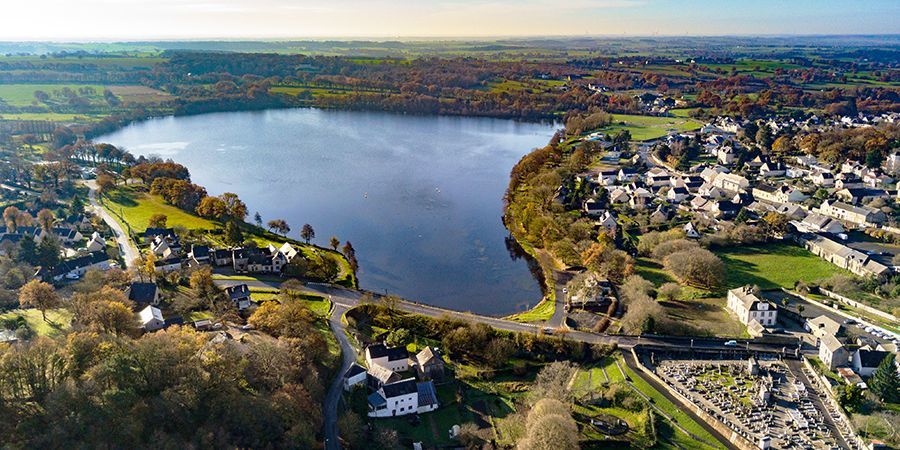 Vue aérienne d’un grand lac entouré d’arbres, de maisons et d’un quartier résidentiel sous un ciel dégagé