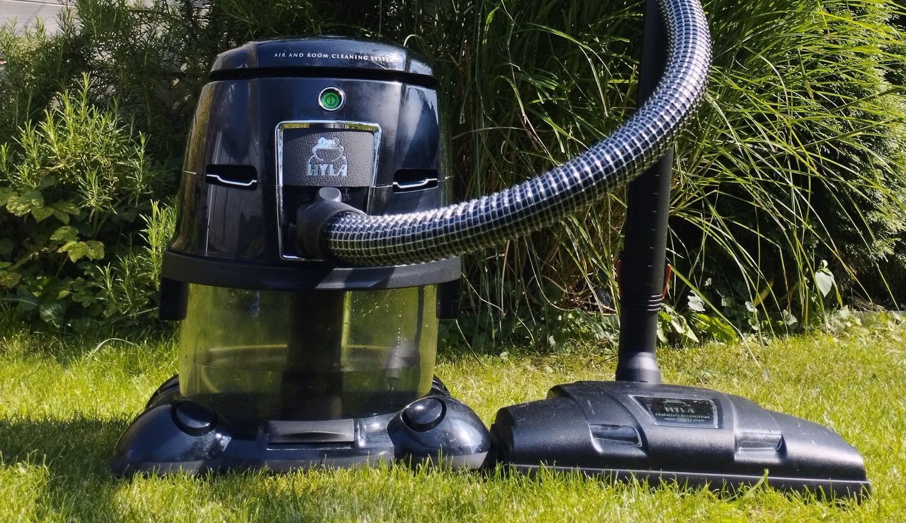 A black vacuum cleaner is sitting on top of a lush green field.