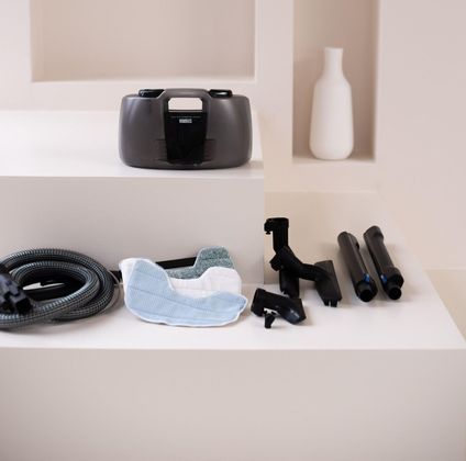 A vacuum cleaner sits on a white shelf next to a vase
